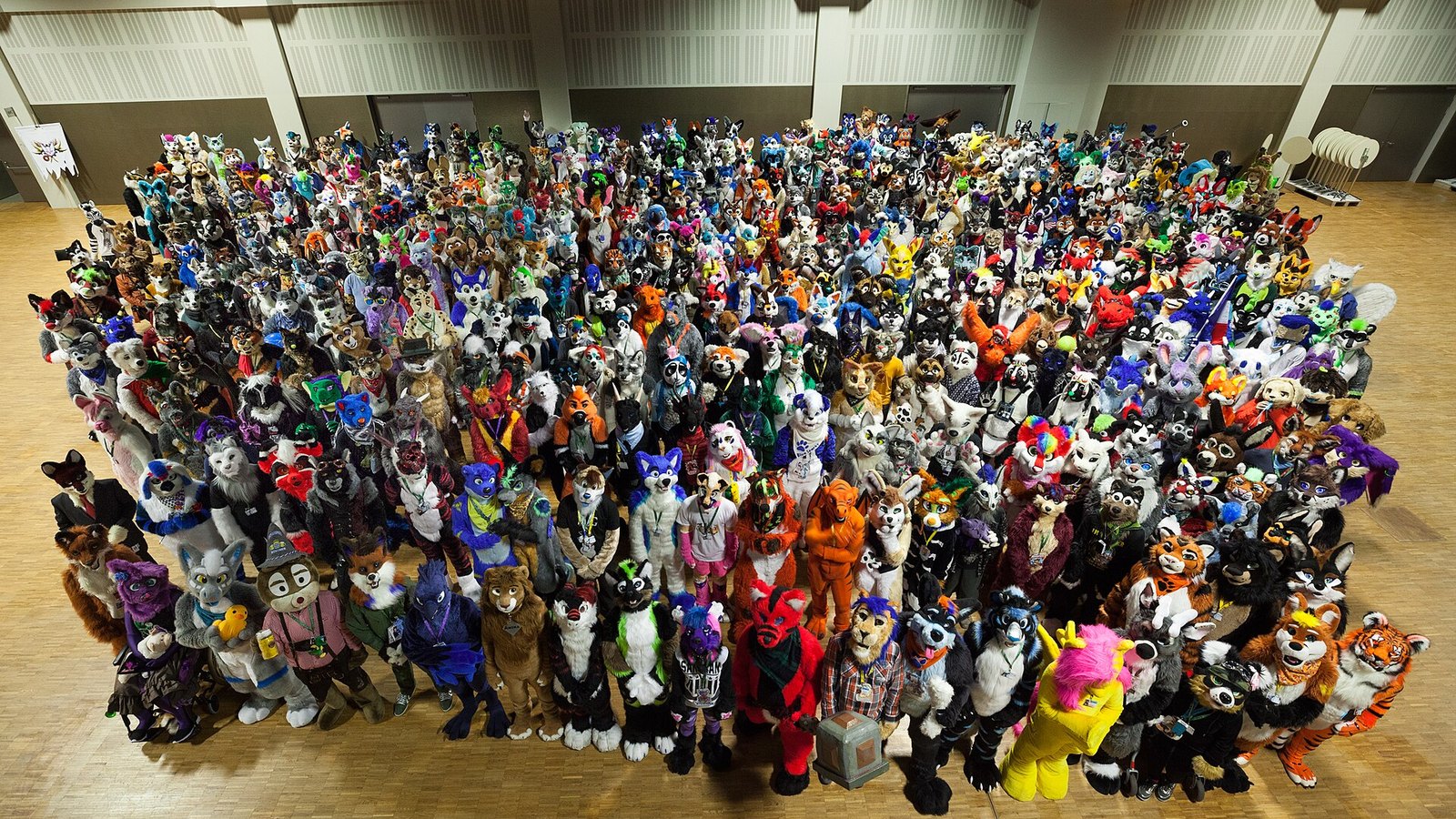 Foto de grupo com centenas de pessoas em fantasias de animais numa convenção furry